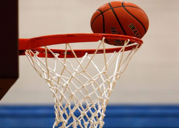 A basketball is in the net and has its head thrown back.