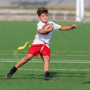 A young boy throwing a football on the field.