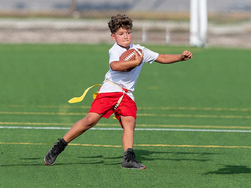 A young boy throwing a football on the field.