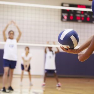 A group of people playing volleyball on a court.