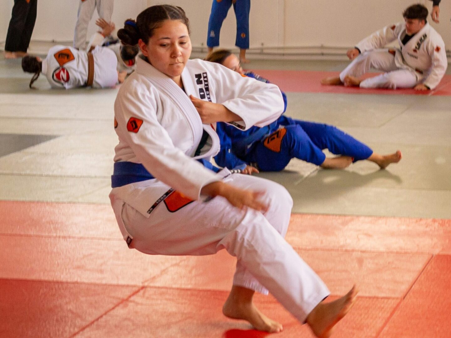 A woman in white and blue uniform doing martial arts moves.